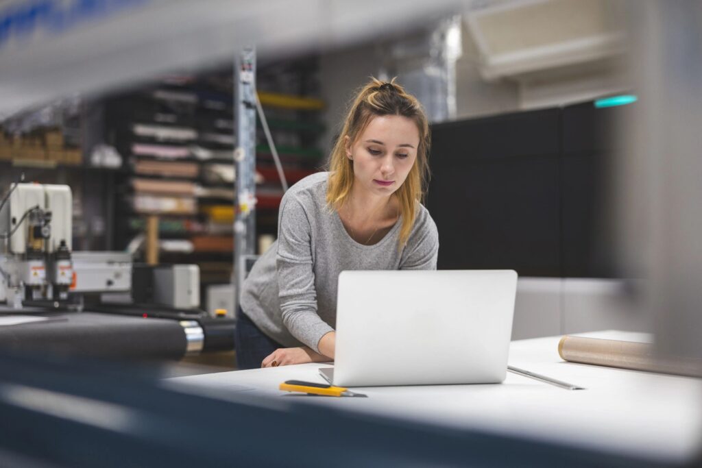 Woman using laptop at printing factory